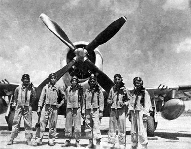 six men stand in front of a large propeller plane