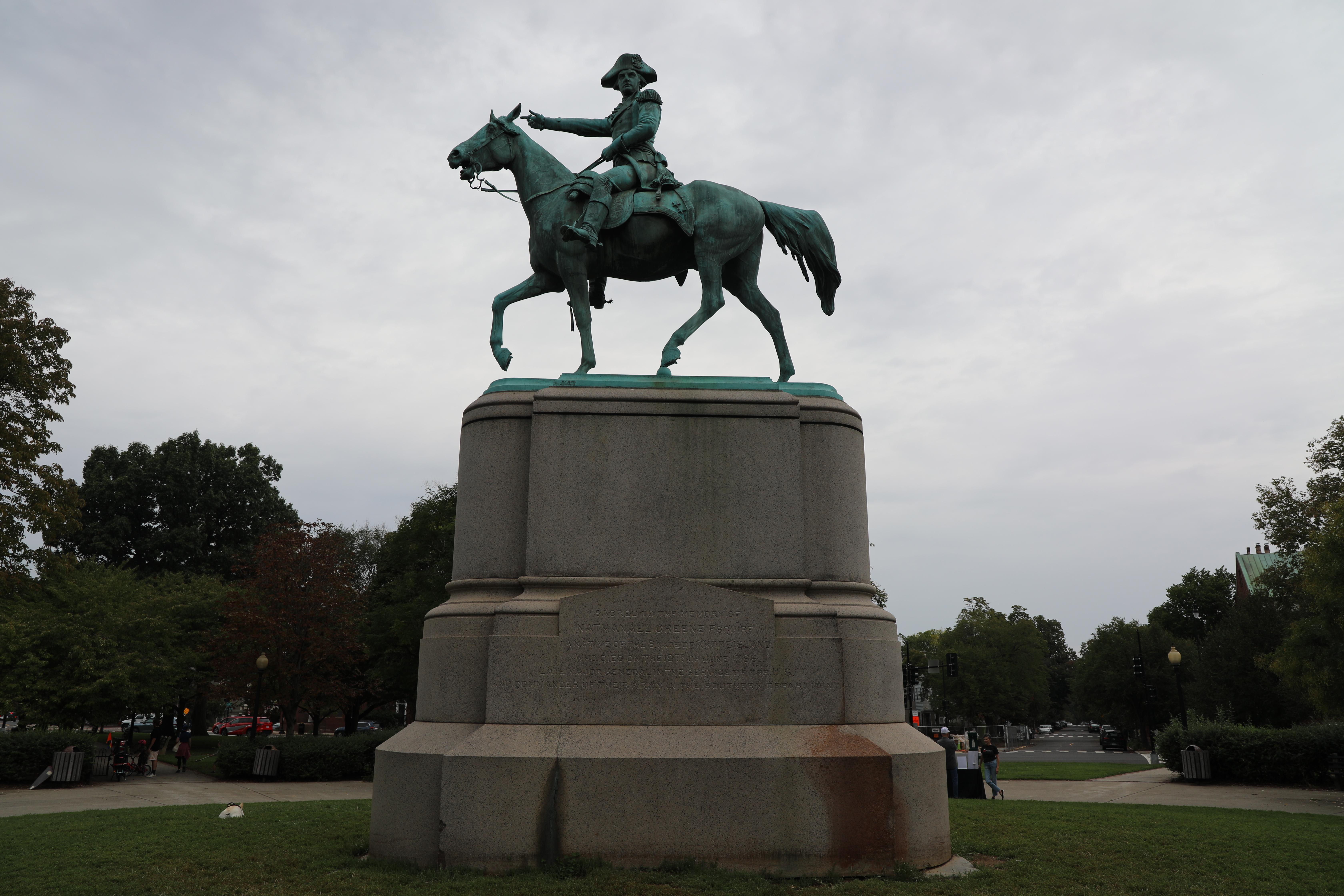 A large bronze equestrian statue of a military figure in uniform sits atop a tall stone pedestal in