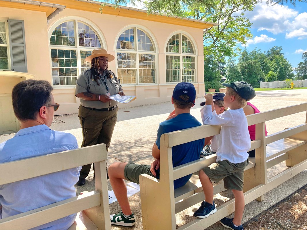 A park ranger talks to a group of visitors seated on benches.