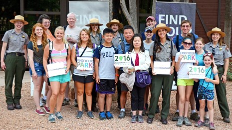 Group of park rangers and visitors with Find Your Park signs