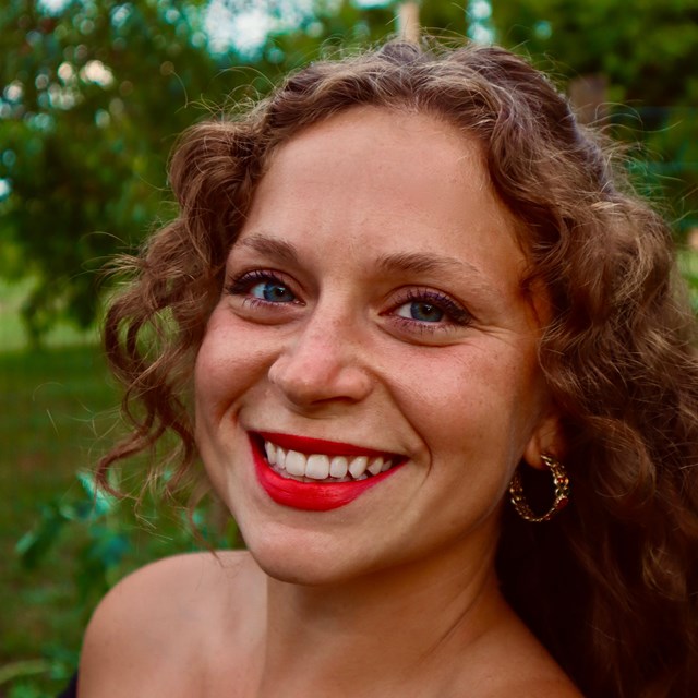 A woman with curly brown hair and a wide smile