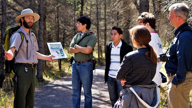 a ranger speaking to five people on a trail in a forest.jpg