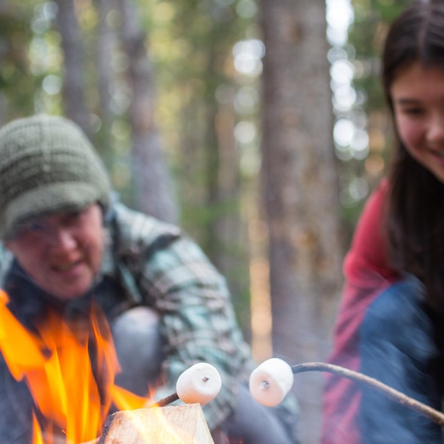 Two campers roasting marshmallows over a flame
