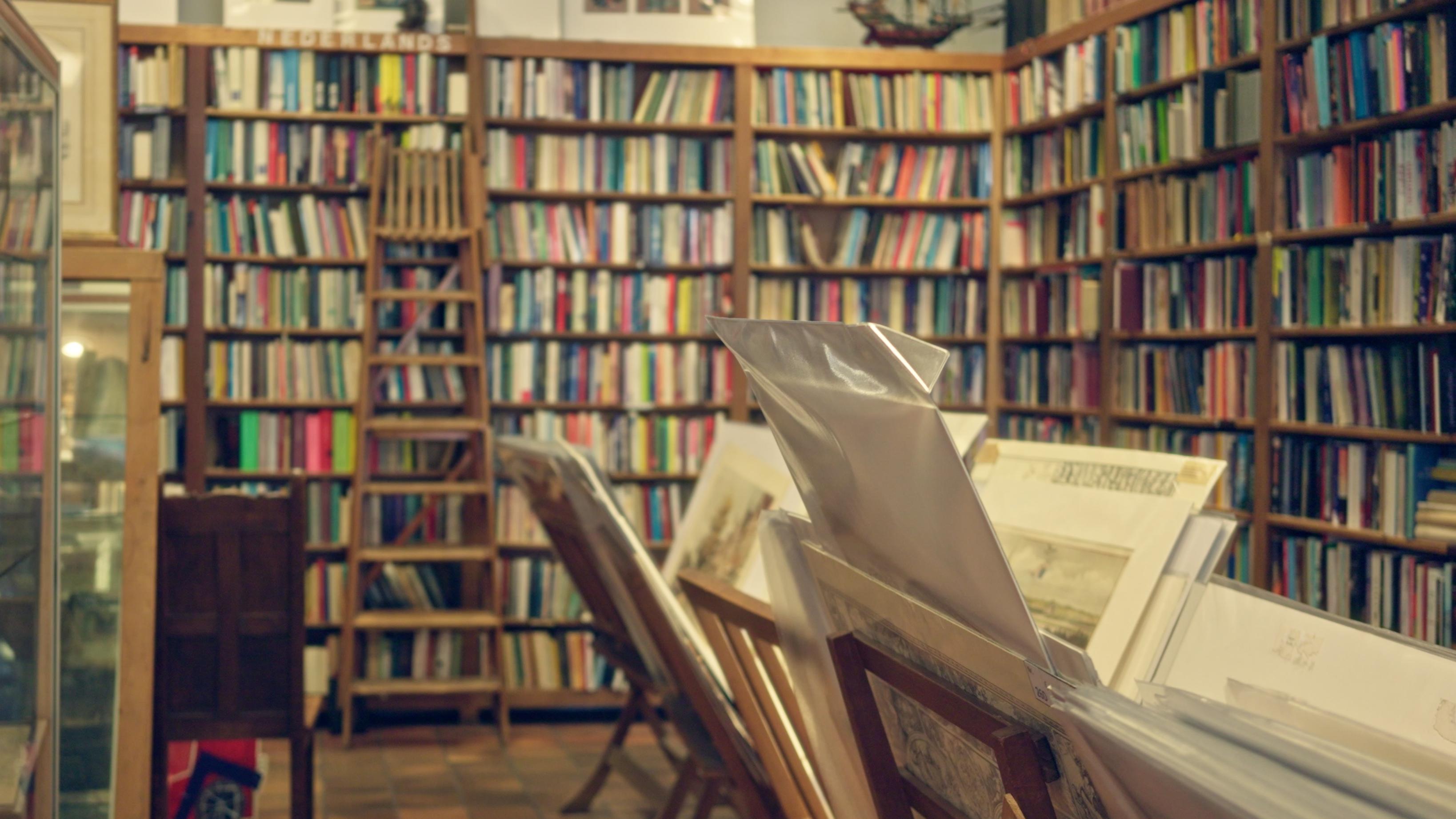 Library setting with books on shelves and maps in holders.