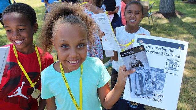 A student smiles, showing her Junior Ranger materials