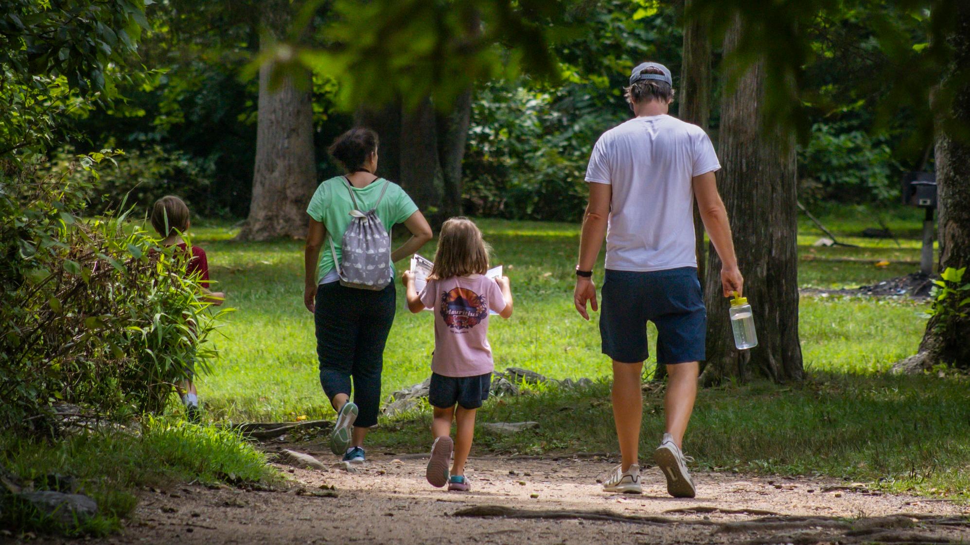 Family of three holding hands on an urban trail