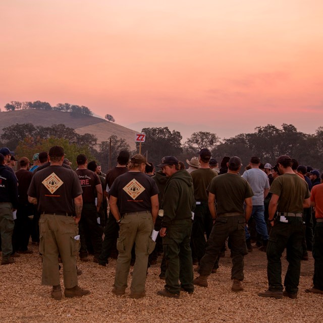 Firefighters attend a briefing at a large wildfire
