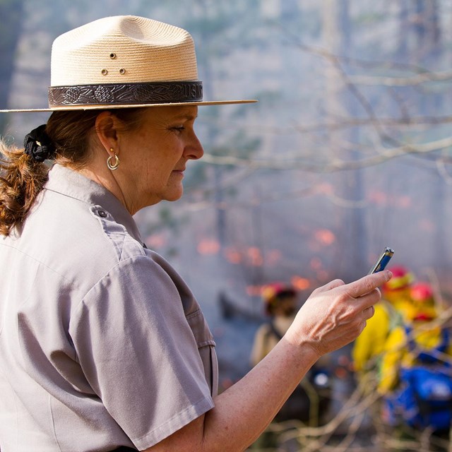 Ranger using smartphone in the field to contact the public about fire.