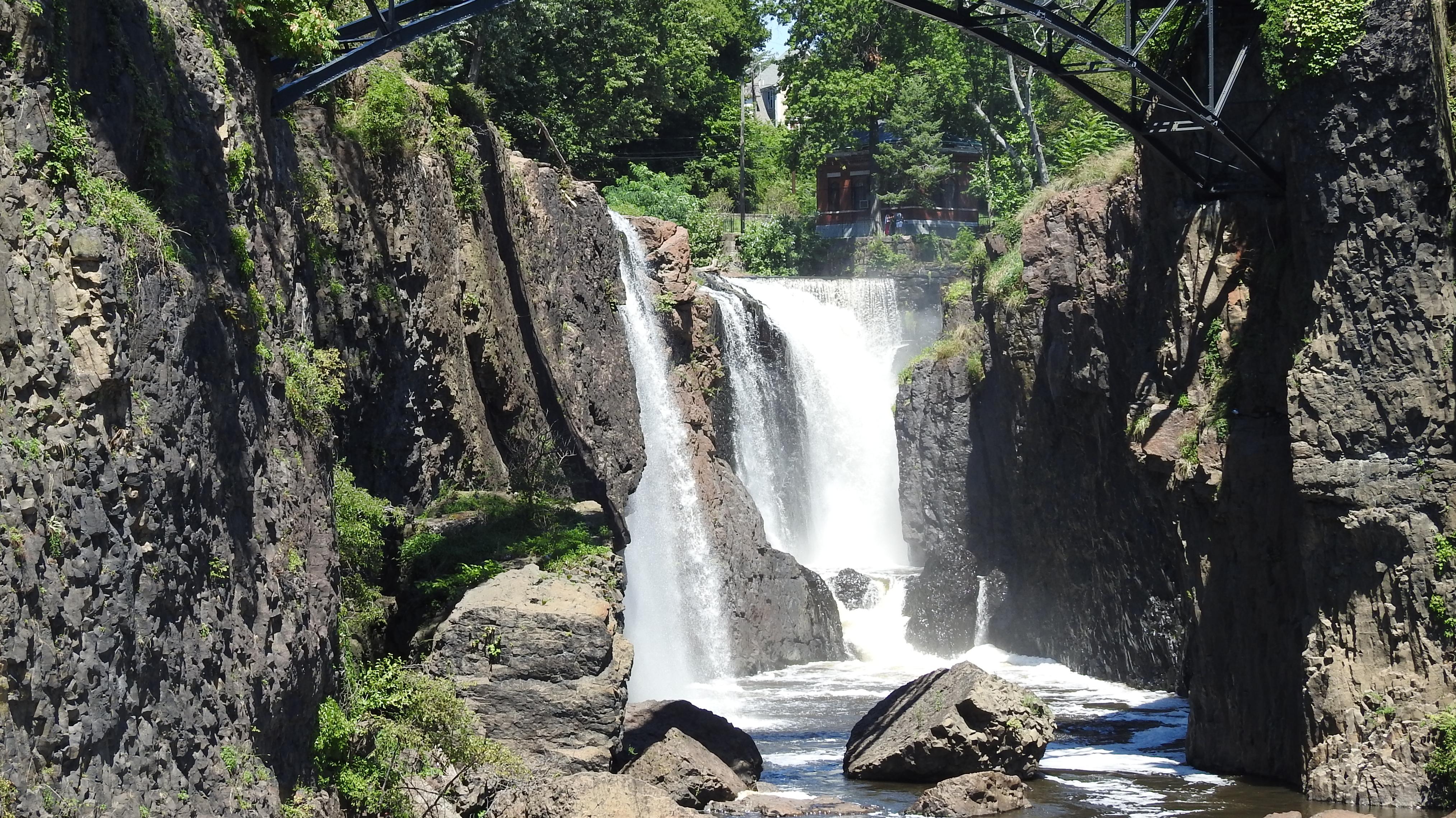 A waterfall seen beneath a bridge.