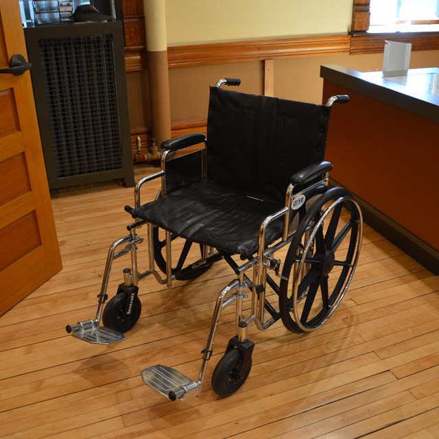 An empty wheelchair next to a desk.