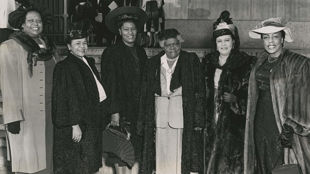 Mary McLeod Bethune and other women stand outside in front of a building