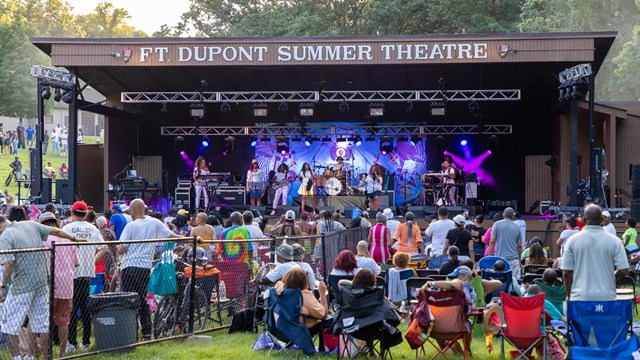 A group of women perform on an outdoor stage.