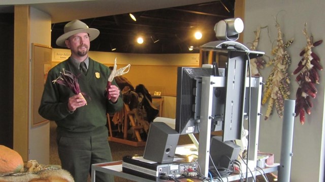 Ranger holding up props in front of a computer and camera