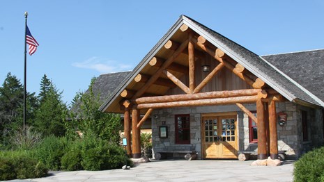A wooden ranger station with a flag pole and patio style entrance