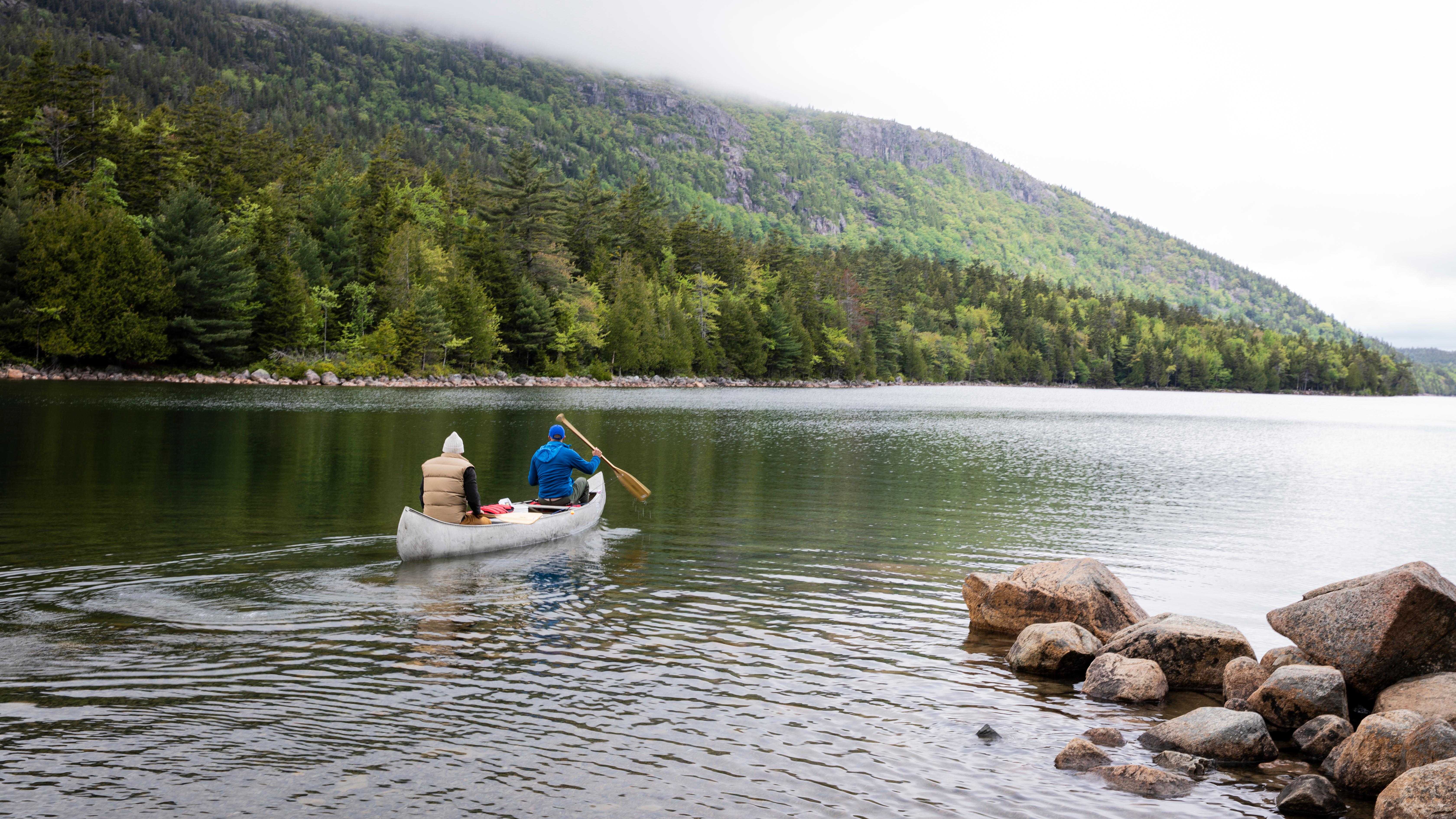 Two people rowing a canoe on a pond
