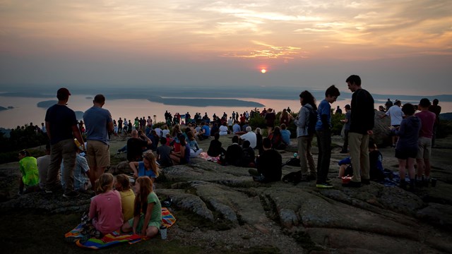 Crowds gather for sunrise on a mountain summit
