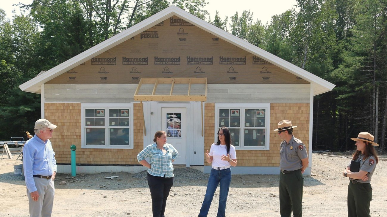 Five people stand in front of newly constructed housing unit
