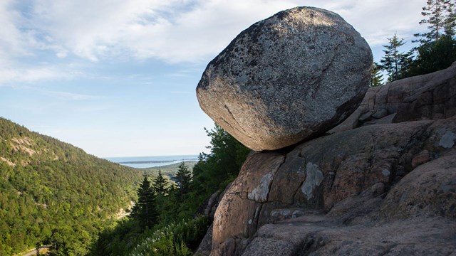 a round boulder perches on a hillside