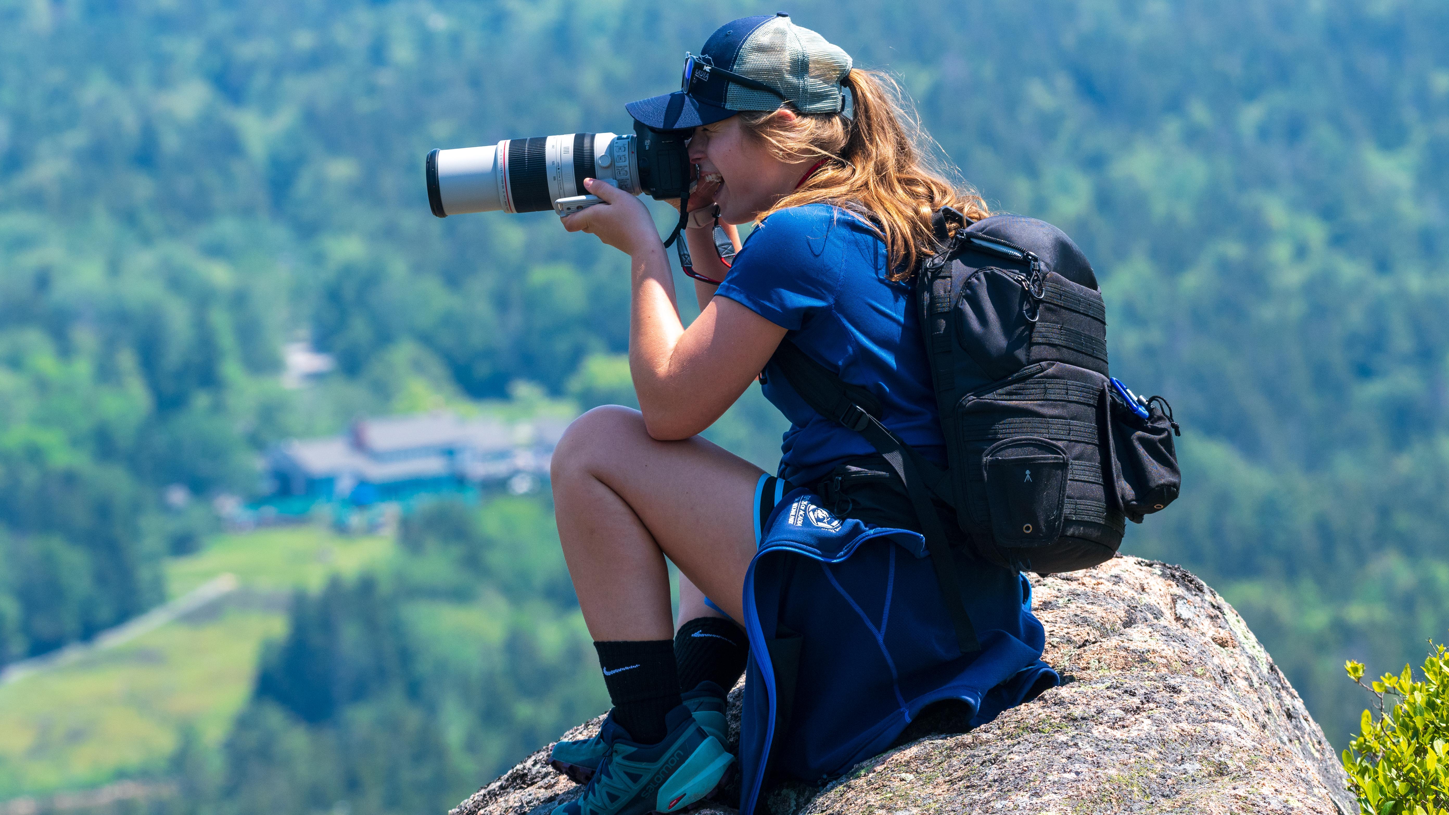A photographer sits on a rock
