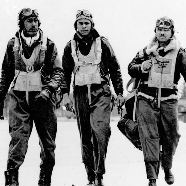4 men walk in WWII era flight ear along a runway