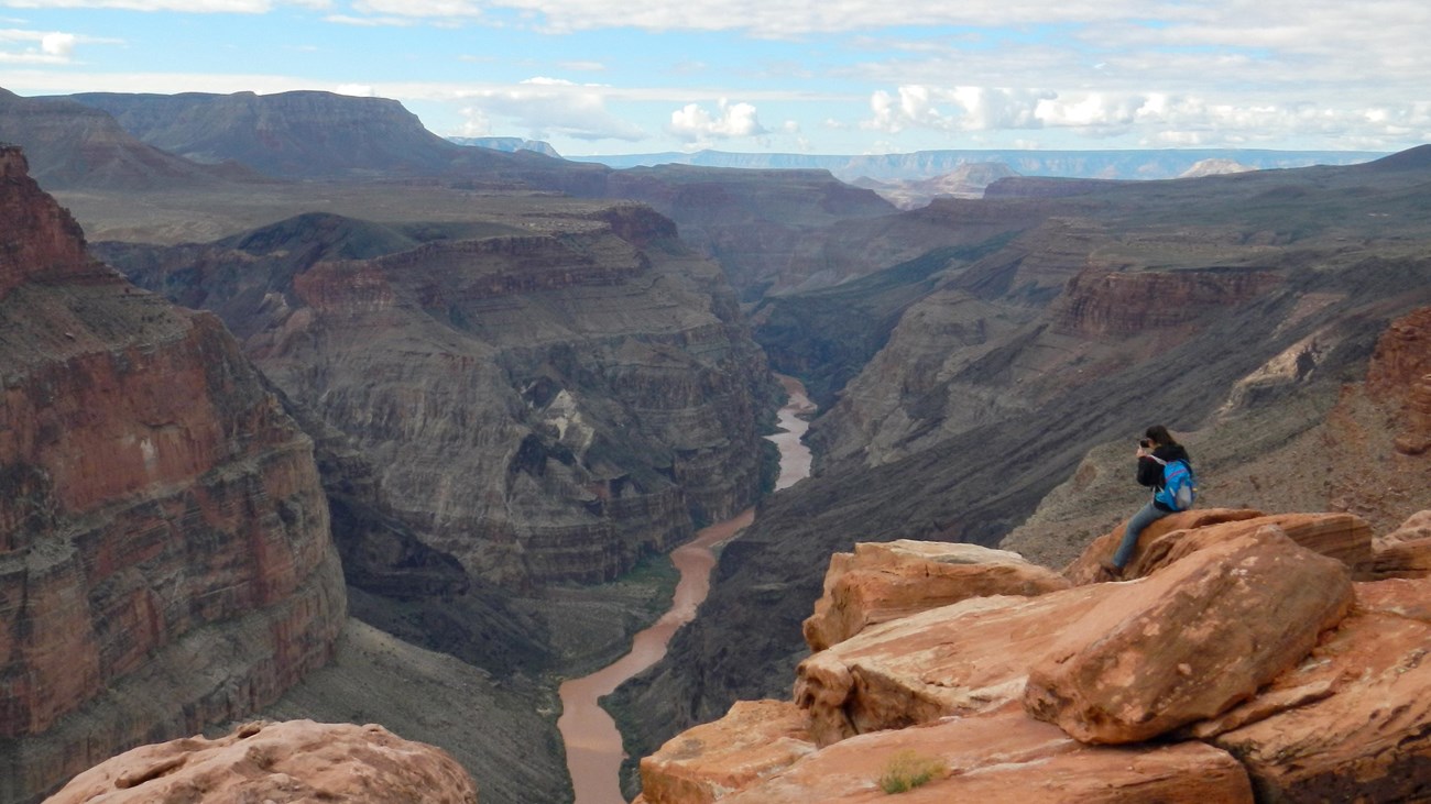 Photo of a photographer high above the Colorado River on the north rim of the Grand Canyon