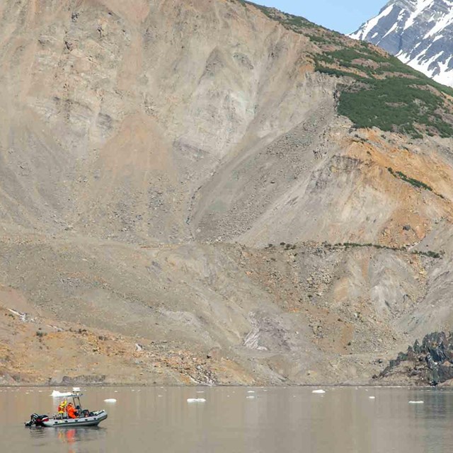 A research skiff in front of a massive landslide.