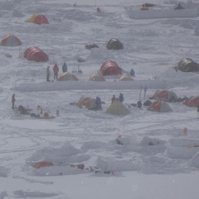 A blizzardy glacial slope with mountain climber camps.