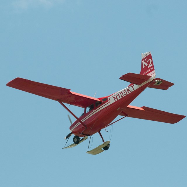 a red plane flying through a blue sky