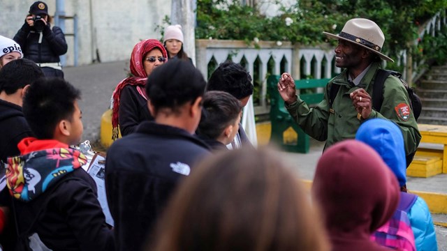 Ranger in uniform and flathat talks to group of students on Alcatraz.