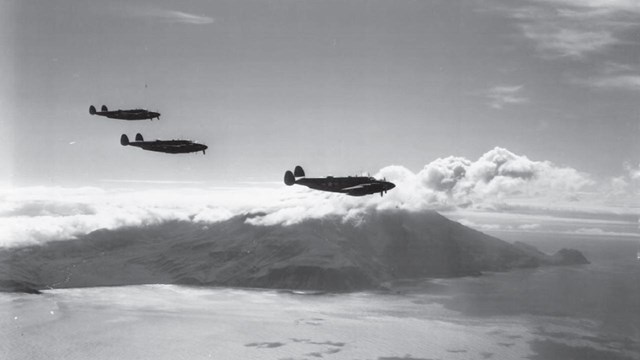 Black and white photo of three planes flying over ocean and mountains