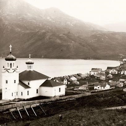 a town along a beach with a large russian church on the far left