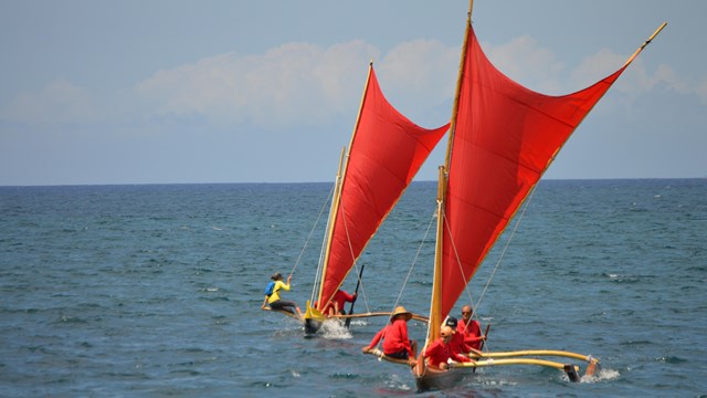 Canoes with red sails in the ocean