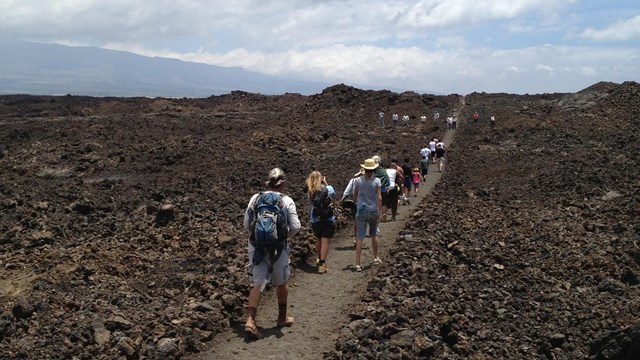 Group of hikers walking along trail through lava