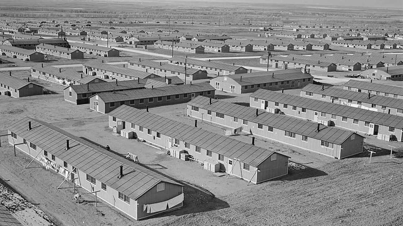 A black and white image depicts closely built long, low houses stretching into the distance