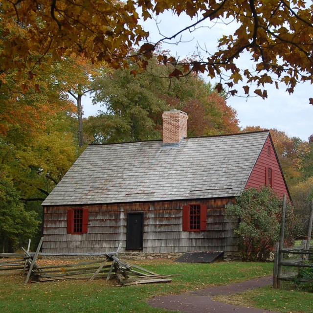 The single story brown wood building with a red brick chimney in the center of the roof