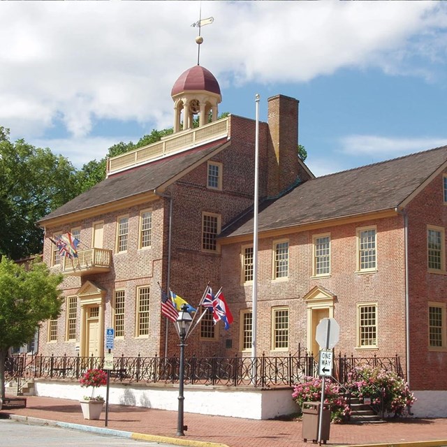 The front and right side of the red brick New Castle Court House are shown on a bright sunny day.