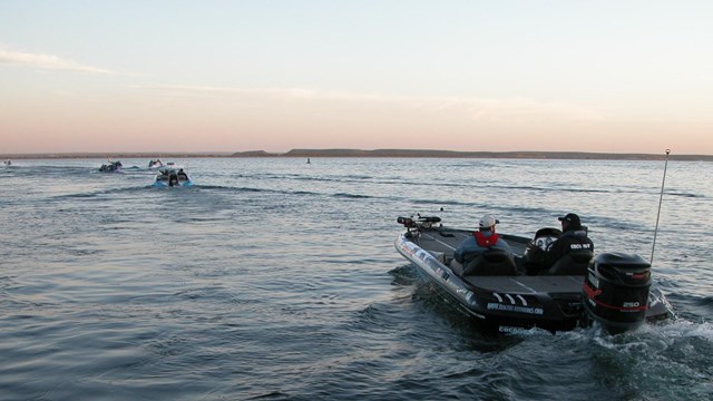 Photo of people in a motorboat with fishing gear.