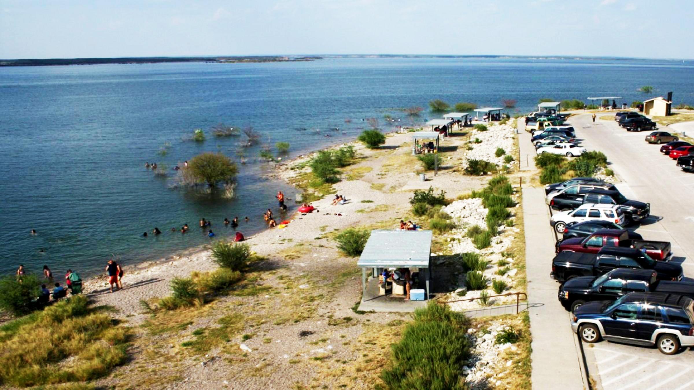 Governors Landing Day Use Area with line of parked vehicles near picnic area and people swimming.