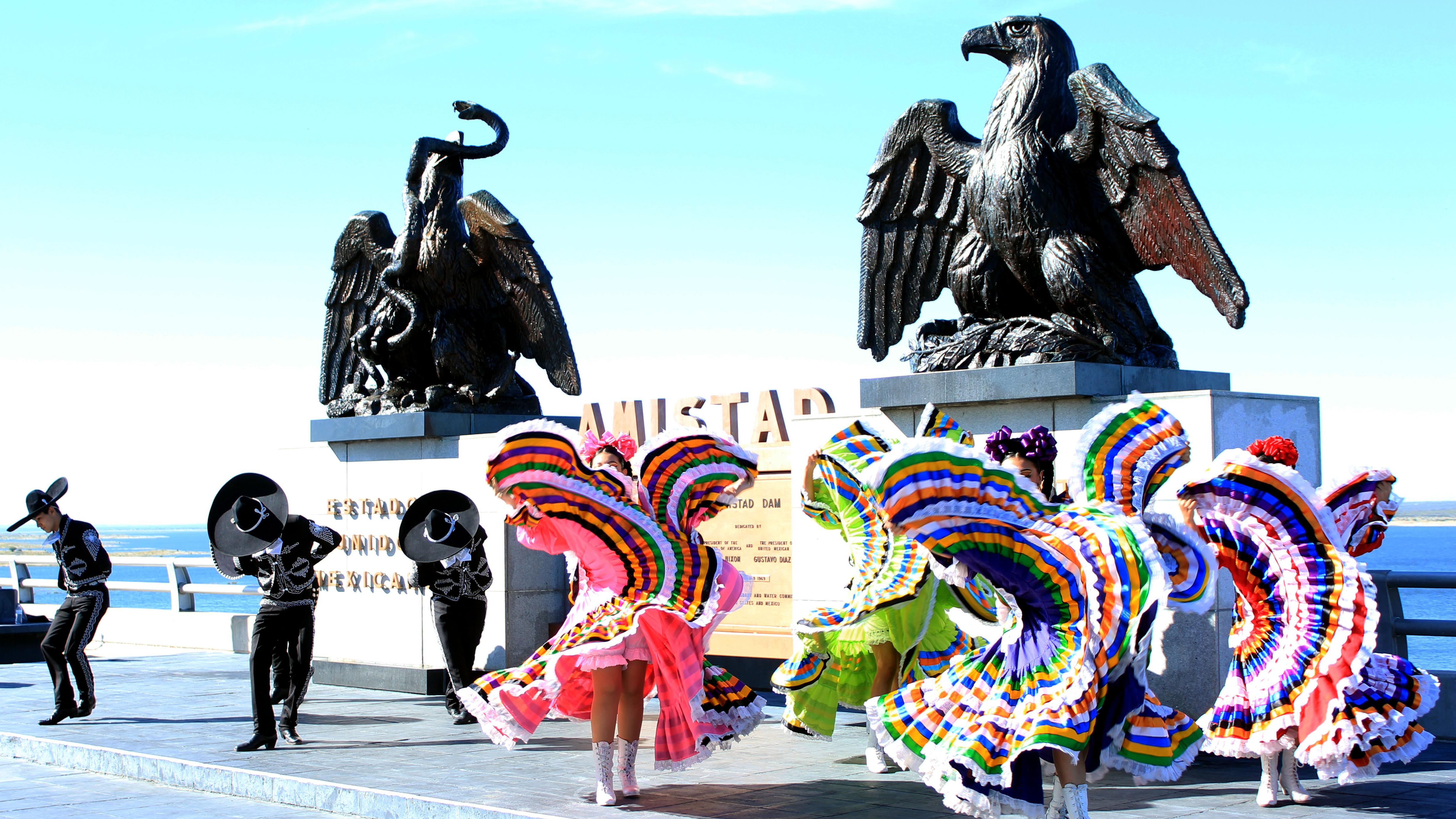 Folklorico dancers performing in front of US and Mexico eagles on Amistad Dam.