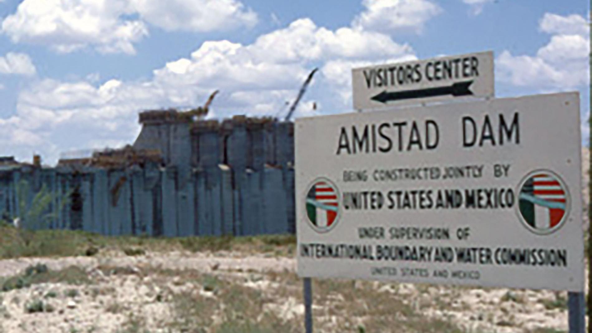 Sign announcing construction of the Amistad Dam, which can be seen in the background.