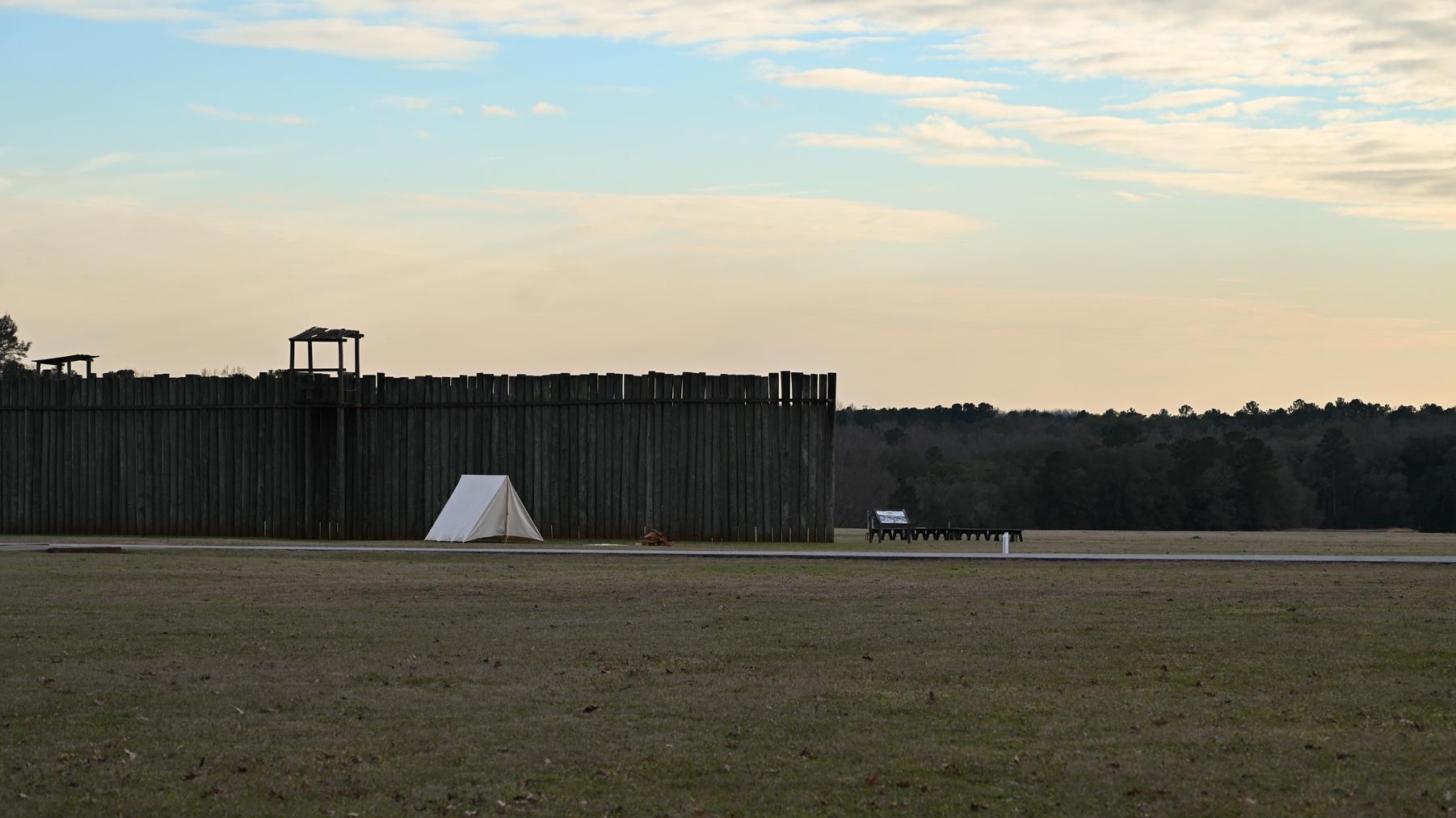 A sunrise view of the Historic Prison Site, the stockade replica sits in the far left of the image.
