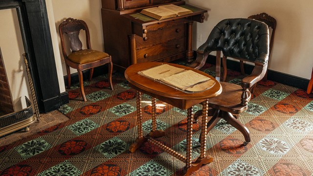 Image of wheeled leather chair in front of a wooden table with documents spread out on top.