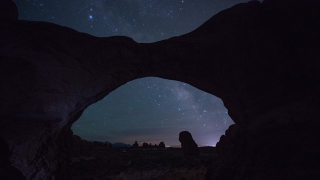 stars and the milky way above a silhouetted arch
