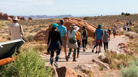 a group of people walk along the trail in Arches