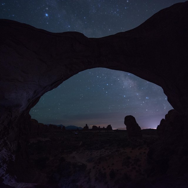stars and the milky way above a silhouetted arch