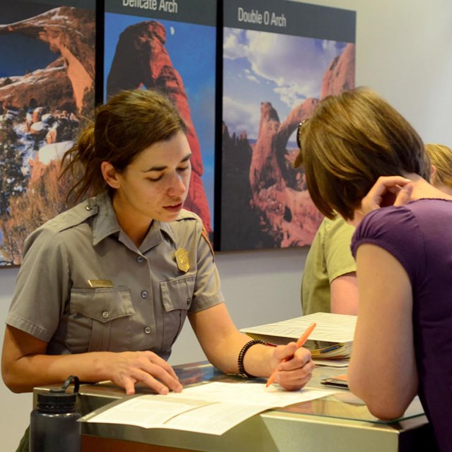 a ranger at an information desk points to a map