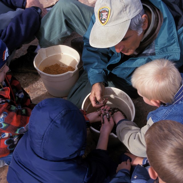 children reach into a pail of gravel