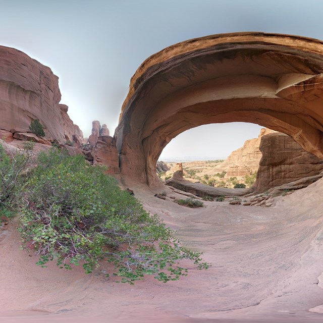 a panoramic image of a broad, stone arch