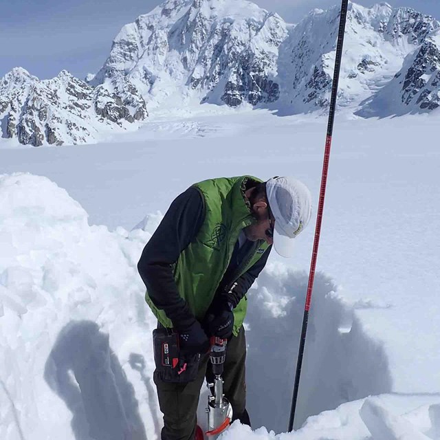 A researcher measures snow depth.