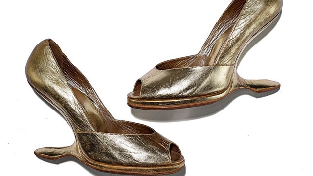 Two gold platform shoes are layered on a white background.